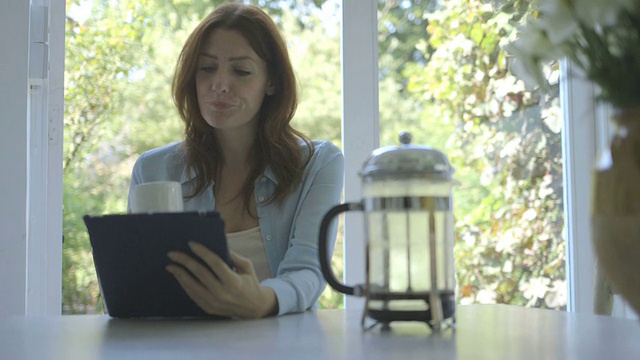 一边喝咖啡一边用平板电脑的女人。视频素材