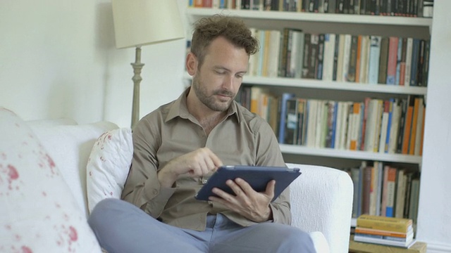 坐在沙发上用平板电脑的男人。视频素材