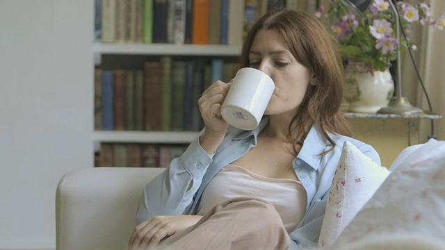 坐在沙发上喝咖啡的女人。视频素材
