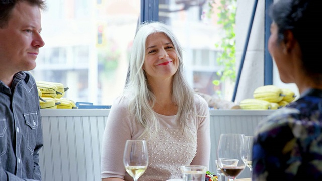 MS微笑成熟的女人坐在餐桌上与丈夫和朋友在餐厅用餐视频素材