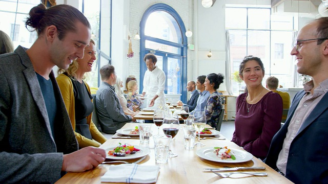 笑着的夫妇一起在餐厅用餐，服务员从桌子上清理盘子在背景视频素材