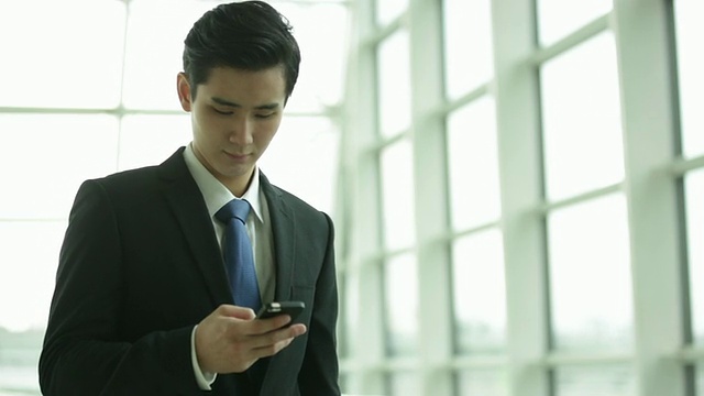 一个年轻人在办公室里用手机发短信。视频下载