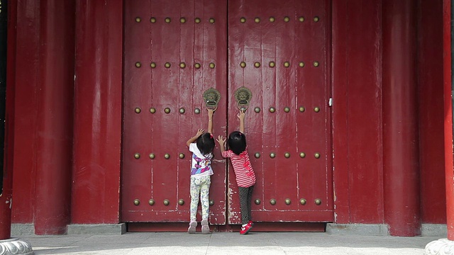 两个小女孩在中国传统的大门前玩耍/陕西西安，中国视频素材