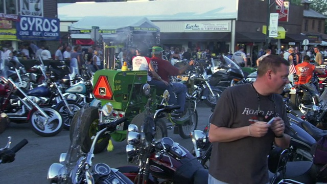 图为美国南达科塔州斯特吉斯摩托车拉力赛期间，一辆打扮成约翰迪尔拖拉机模样的摩托车在大街上巡航视频素材