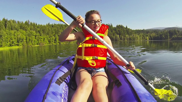 一个女孩在湖中划着皮划艇视频素材