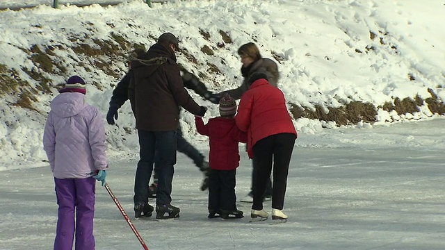 尼芬堡，两个大人和一个孩子在溜冰，雪，冰冻的河视频素材