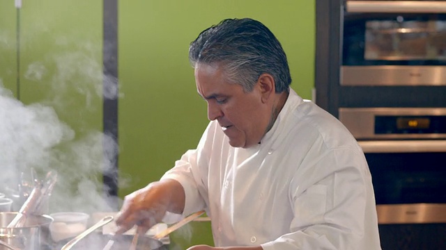 MS男厨师在厨师挑战比赛中快速搅拌食物在煎锅和样品品尝与茶匙视频下载
