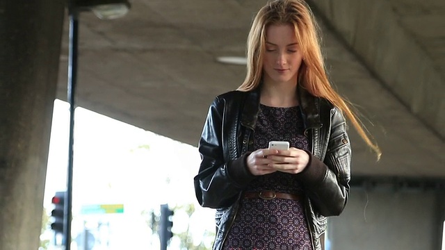 年轻女子使用智能手机走路。视频素材