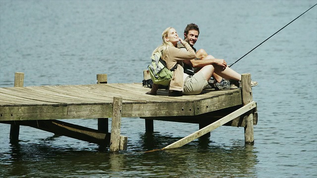 一对夫妇坐在码头上钓鱼视频素材