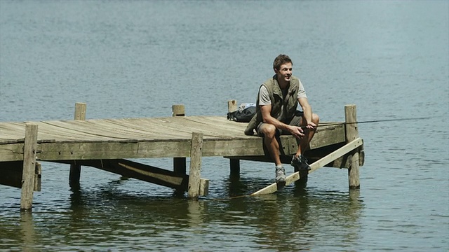 一个男人坐在防波堤上钓鱼视频素材