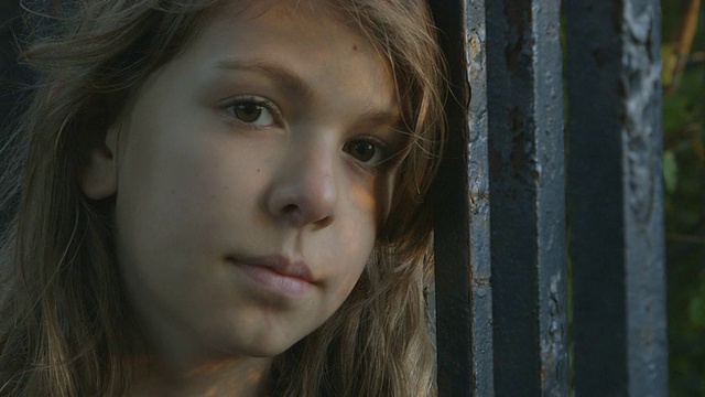 一个小女孩在篱笆旁微笑视频素材