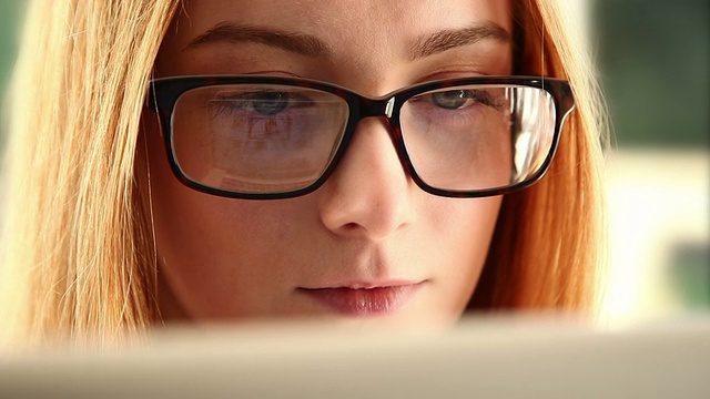在线学习，戴眼镜的年轻女子。视频素材