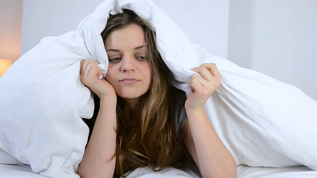一个疲惫的女人躺在床上准备睡觉的照片/大伦敦，英国视频素材