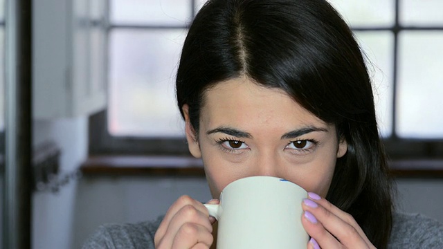 一名女子微笑着啜饮咖啡/大伦敦，英国视频素材