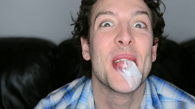 一名男子吹口香糖泡泡直到泡泡破裂的照片/大伦敦，英国视频下载