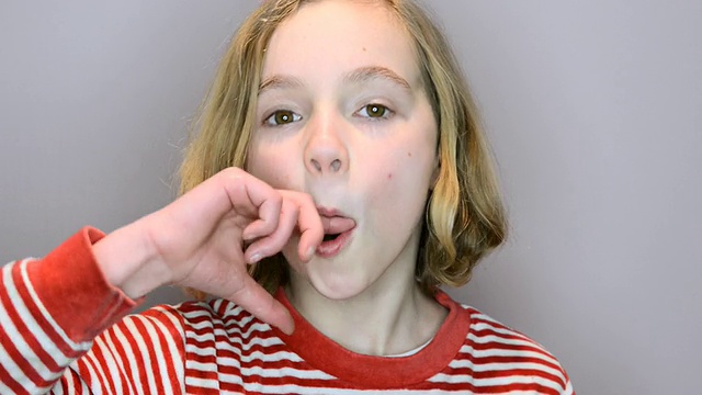 小女孩用手指叼着嘴发出爆裂声的照片/伦敦，大伦敦，英国视频素材