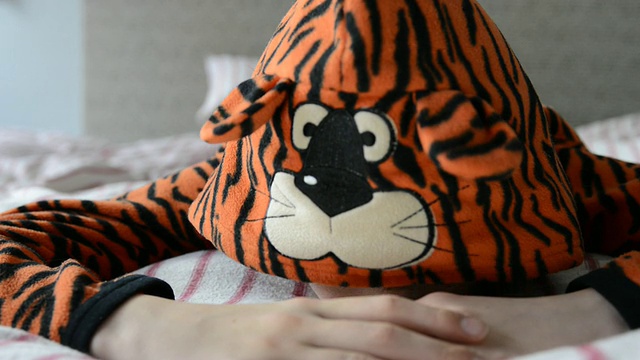 大伦敦，英国伦敦，男孩穿着老虎睡衣躺在床上，看起来很累视频素材