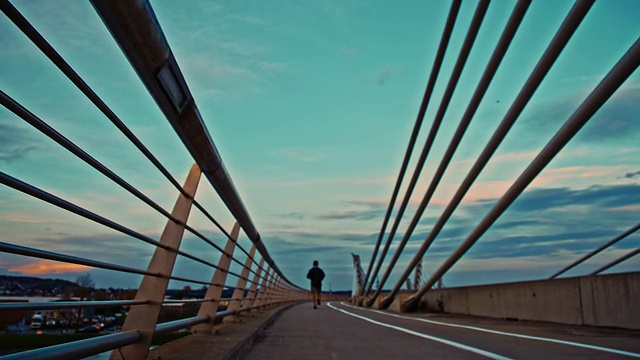 一名男子在黄昏时慢跑过桥视频素材