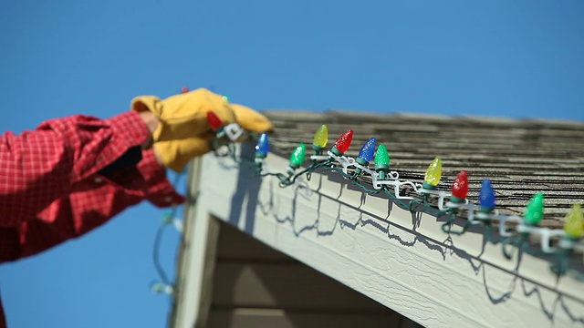 一名男子正在屋顶上安装LED圣诞灯视频下载