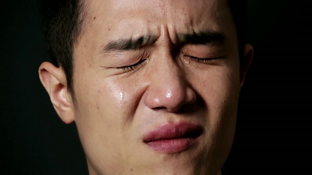 韩国首尔，一名男子在黑色背景下流泪视频下载