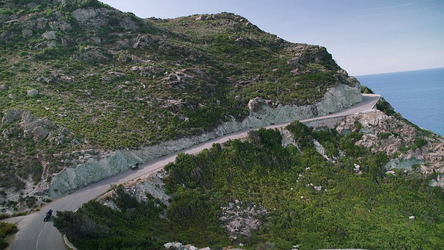 两个骑自行车的人沿着海边的一条山路前进视频素材