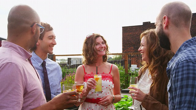 在夏天的晚上，夫妇加入一群朋友在屋顶花园喝酒视频素材