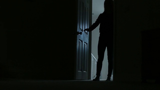 苗条的年轻女性的剪影进入一个黑暗的房间。视频下载