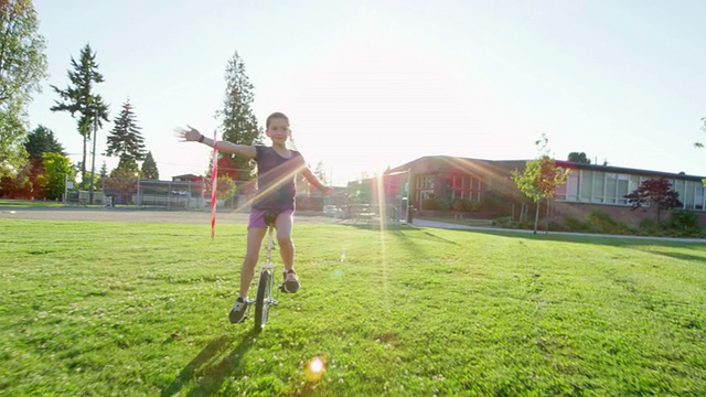 MS TS SLO MO微笑的年轻女孩在学校附近的操场上骑独轮车呼啦圈视频素材