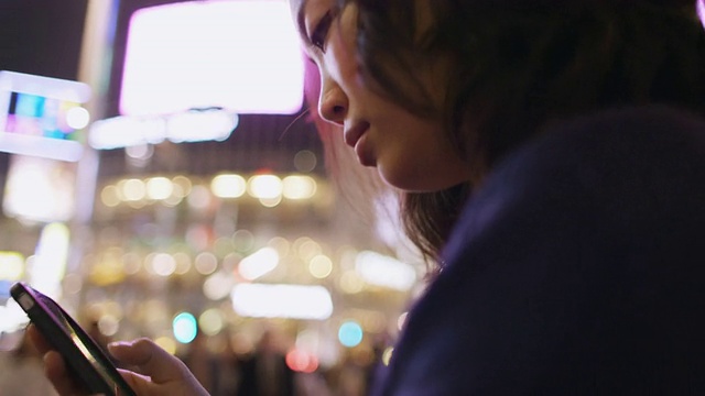 在日本东京涩谷，一名年轻的日本女子正在查看她的智能手机视频素材