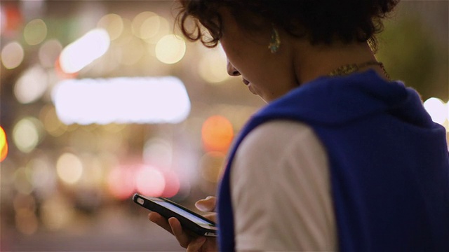 在日本东京涩谷，一名年轻的日本女子在查看她的智能手机视频下载