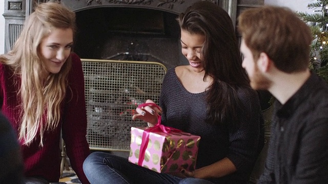 年轻的女人在圣诞节期间从朋友那里收到礼物视频素材