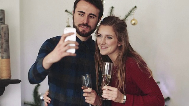 圣诞节期间，一名年轻男子和一名女子手持香槟酒杯自拍视频素材