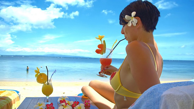 在海滩上喝着鸡尾酒放松的女士视频素材