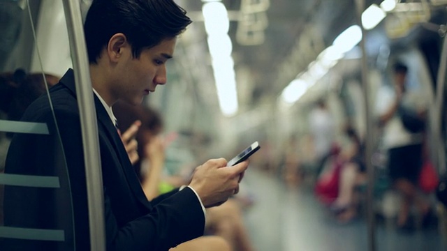 加州大学的年轻商人在地铁上使用智能手机视频下载