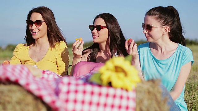 三个女孩在野餐时吃桃子视频下载