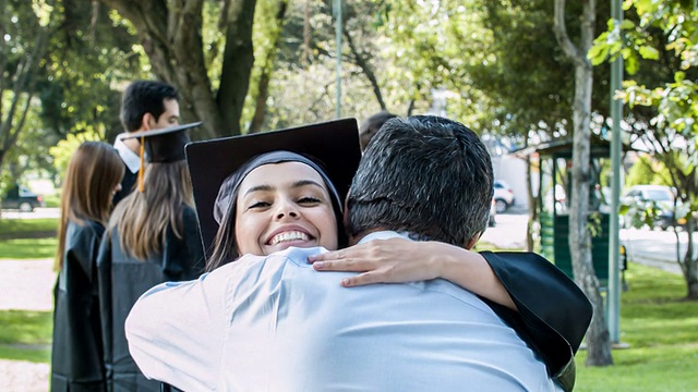 快乐的毕业女子拥抱她骄傲的父亲视频素材