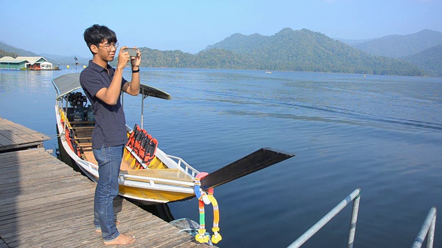 近景:年轻男子在湖上拍照视频下载