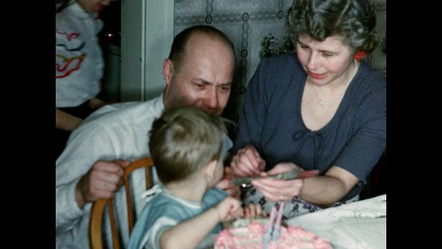 男孩在父母的帮助下切蛋糕视频素材