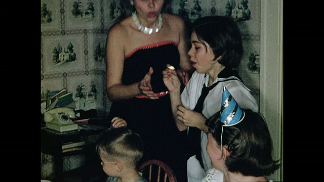 20世纪50年代的女孩在吹生日蜡烛时烧伤了手指，切蛋糕视频下载