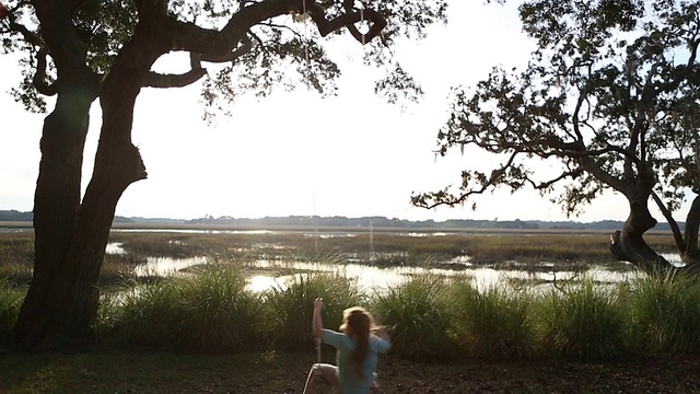 8岁的小女孩在沼泽低地的秋千上荡秋千视频素材