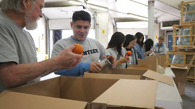 高级男子整理捐赠箱与不同团体的食品银行志愿者视频下载