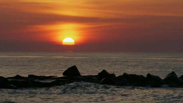 实时长焦拍摄的橙色太阳刚刚在海洋地平线上，云彩后面，埃文海边，新泽西，大西洋视频下载