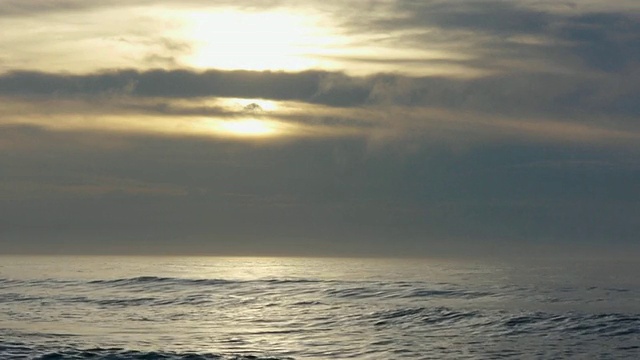 戏剧性的光和云，太阳从风暴云之上升起，明亮的，银色的倒影在水面上，埃文海岸，新泽西州，大西洋视频下载