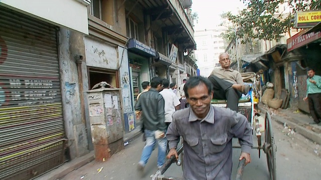 人力车车夫拉着人力车走在印度孟加拉西部加尔各答的路上视频下载