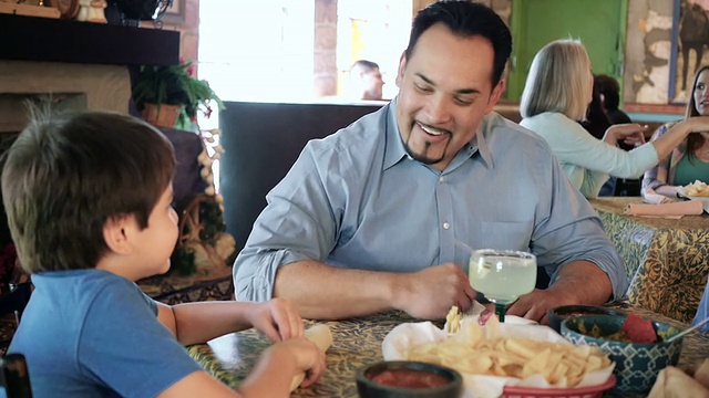 成熟的西班牙父亲与年幼的儿子在餐厅用餐视频素材
