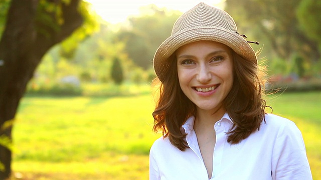 高清:美丽微笑的女人在夏季绿色公园的肖像。视频素材