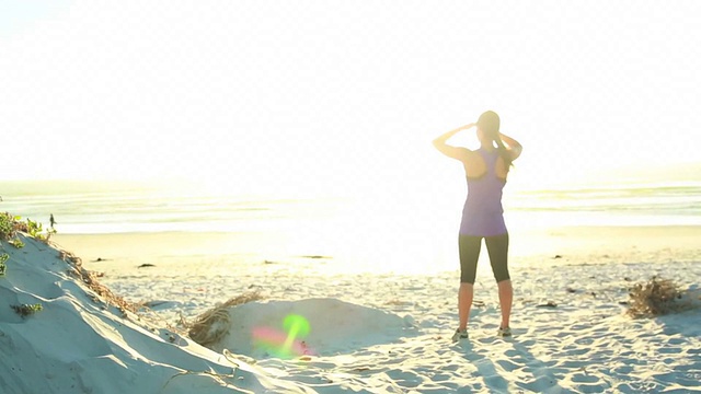 日落时在海滩上锻炼的女人视频素材