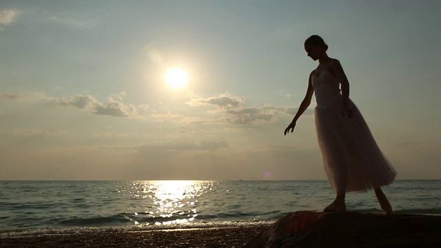 日落时在海岸上有一个芭蕾舞女演员视频素材