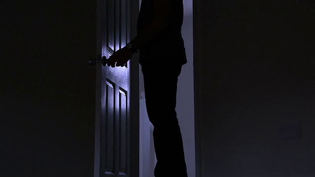 一个男人离开黑暗房间的剪影，从左到右。视频素材