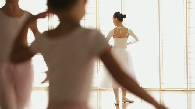一名芭蕾舞演员和年轻的女孩在前景中跳舞。视频下载